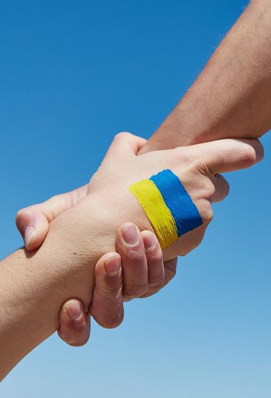 Zwei Hände greifen sich gegenseitig mit einer Ukraine Flagge auf dem Handrücken