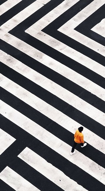 Frau in gelb läuft über schwarz-weiß gestrichene Straße