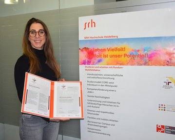 Anni Pröll, Diversitäts-Beauftragte der SRH Hochschule Heidelberg, hält das Zertifikat familiengerechte Hochschule in den Händen.