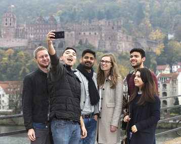 Internationale Studierende machen ein Selfie auf der alten Brücke