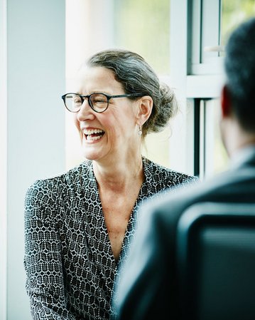 Frau mit Brille lacht während eines Gesprächs