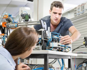 Studierende reparieren einen Roboter-Arm