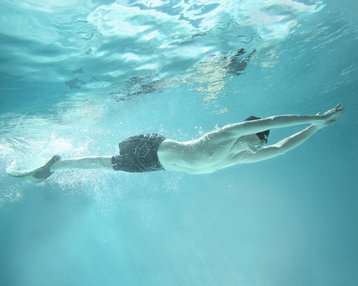 Mann im Schwimmbad unter Wasser