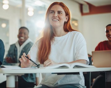 Studentin mit langen roten Haaren sitzt in einer Vorlesung