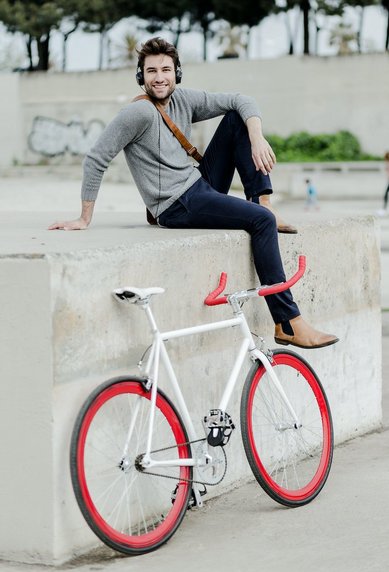 Junger Mann auf Mauer mit seinem Fahrrad im Vordergrund