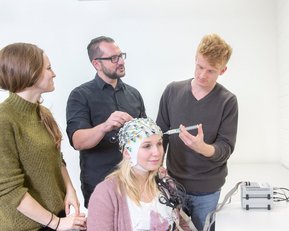 Anhand von EEG-Hauben, hier im Test mit Studierenden und Prof. Dr. Patric Meyer (Mitte), können die Forscher messen, welchen Einfluss der Wechsel zwischen zwei Sprachen auf das Gehirn hat. 