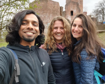 Mohnish, Kathrin und Jeyhuna schießen ein Selfie vor einer Burg Ruine.